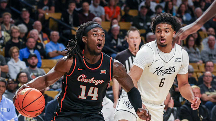 Mar 5, 2025; Orlando, Florida, USA; Oklahoma State Cowboys guard Jamyron Keller (14) drives to the basket in front of UCF Knights guard Dallan Coleman (6) during the first half at Addition Financial Arena. Mandatory Credit: Mike Watters-Imagn Images