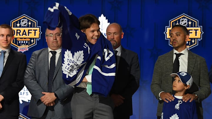 Jun 28, 2023; Nashville, Tennessee, USA; Toronto Maple Leafs draft pick Easton Cowan puts on his sweater after being selected with the twenty eighth pick in round one of the 2023 NHL Draft at Bridgestone Arena. Mandatory Credit: Christopher Hanewinckel-Imagn Images Jun 28, 2023; Nashville, Tennessee, USA; Toronto Maple Leafs draft pick Easton Cowan puts on his sweater after being selected with the twenty eighth pick in round one of the 2023 NHL Draft at Bridgestone Arena. Mandatory Credit: Christopher Hanewinckel-Imagn Images