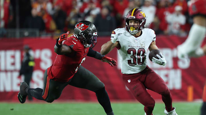 Jan 12, 2025; Tampa, Florida, USA; Washington Commanders running back Austin Ekeler (30) runs against Tampa Bay Buccaneers linebacker Yaya Diaby (0) during the fourth quarter of a NFC wild card playoff at Raymond James Stadium. Mandatory Credit: Kim Klement Neitzel-Imagn Images