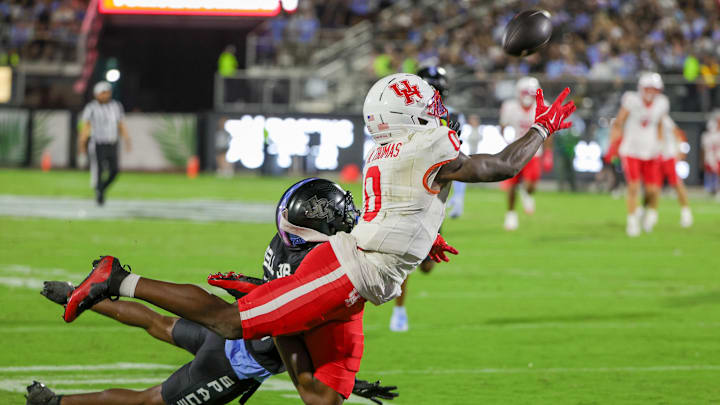 Nov 7, 2025; Orlando, Florida, USA; Houston Cougars wide receiver Amare Thomas (0) dives to catch a pass against UCF Knights defensive back DJ Bell (5) during the first quarter at Acrisure Bounce House. Mandatory Credit: Mike Watters-Imagn Images