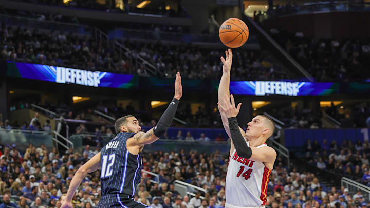 Dec 26, 2024; Orlando, Florida, USA; Miami Heat guard Tyler Herro (14) shoots against Orlando Magic guard Trevelin Queen (12) during the second quarter at Kia Center. Mandatory Credit: Mike Watters-Imagn Images