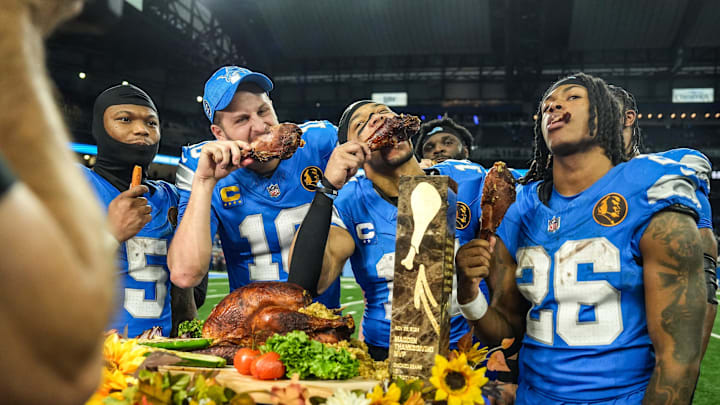 Lions quarterback Jared Goff (16), defensive tackle DJ Reader (98), wide receiver Amon-Ra St. Brown (14), running back Jahmyr Gibbs (26) and linebacker Al-Quadin Muhammad (69) celebrate their win against the Bears with a turkey drumstick Thanksgiving Day in Detroit.