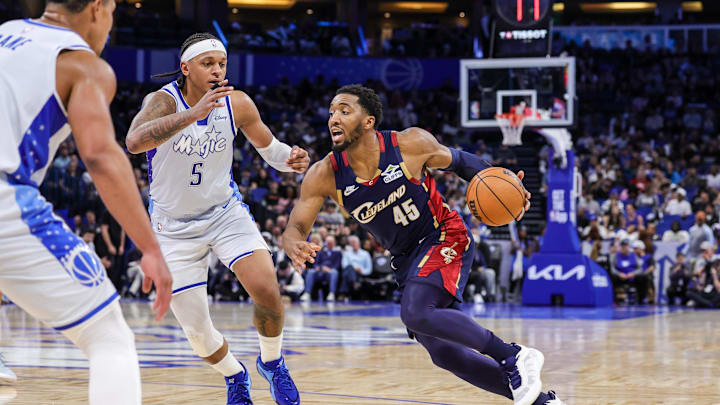 Mar 11, 2026; Orlando, Florida, USA; Cleveland Cavaliers guard Donovan Mitchell (45) drives around Orlando Magic forward Paolo Banchero (5) during the second half at Kia Center. Mandatory Credit: Mike Watters-Imagn Images