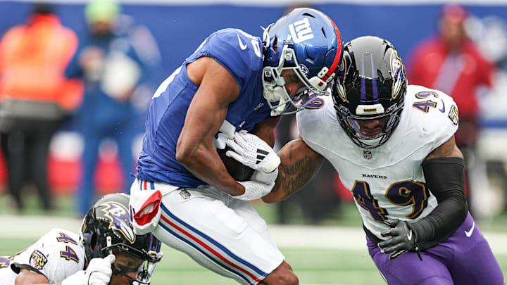 Dec 15, 2024; East Rutherford, New Jersey, USA; New York Giants wide receiver Darius Slayton (86) is tackled by Baltimore Ravens linebacker Chris Board (49) and cornerback Marlon Humphrey (44) during the first half at MetLife Stadium. Mandatory Credit: Vincent Carchietta-Imagn Images