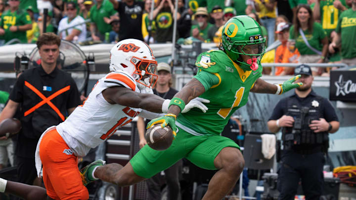 Oregon’s Dakorien Moore, right, flies over the goal line ahead of Oklahoma State’s David Kabongo for a second quarter touchdown at Autzen.