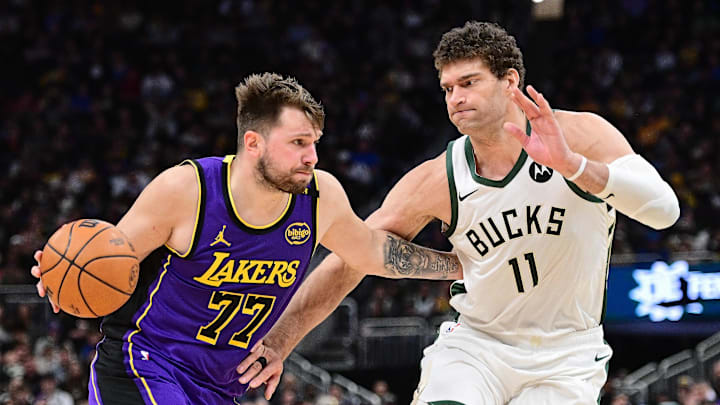 Mar 13, 2025; Milwaukee, Wisconsin, USA; Los Angeles Lakers guard Luka Doncic (77) drives to the basket against Milwaukee Bucks center Brook Lopez (11) in the fourth quarter at Fiserv Forum. Mandatory Credit: Benny Sieu-Imagn Images