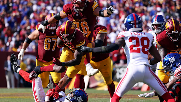 Sep 15, 2024; Landover, Maryland, USA; Washington Commanders running back Brian Robinson Jr. (8) runs the ball against New York Giants linebacker Bobby Okereke (58) during the fourth quarter at Commanders Field. Mandatory Credit: Peter Casey-Imagn Images