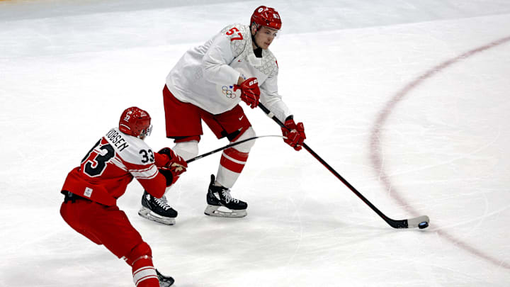 Feb 11, 2022; Beijing, China;  ROC defender Alexander Nikishin (57) passes the puck against  Denmark forward Julian Jakobsen (33) in men's ice hockey Group B play during the Beijing 2022 Olympic Winter Games at National Indoor Stadium. Mandatory Credit: Peter Casey-Imagn Images