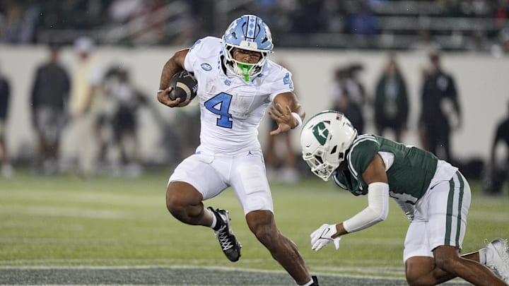Sep 6, 2025; Charlotte, North Carolina, USA;  North Carolina Tar Heels running back Caleb Hood (4) tries to avoid Charlotte 49ers defensive back Gavin Shipman (4) during the second half at Jerry Richardson Stadium. 