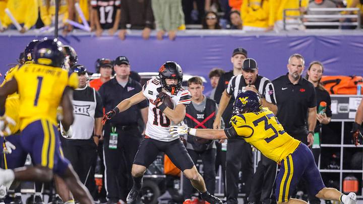 Sep 26, 2026; Morgantown, West Virginia, USA; Oklahoma State Cowboys wide receiver Wyatt Young (10) catches a pass and shakes a tackle from West Virginia Mountaineers linebacker Ashton Woods (33) during the first quarter at Milan Puskar Stadium. Mandatory Credit: Ben Queen-Imagn Images Sep 26, 2026; Morgantown, West Virginia, USA; Oklahoma State Cowboys wide receiver Wyatt Young (10) catches a pass and shakes a tackle from West Virginia Mountaineers linebacker Ashton Woods (33) during the first quarter at Milan Puskar Stadium. Mandatory Credit: Ben Queen-Imagn Images