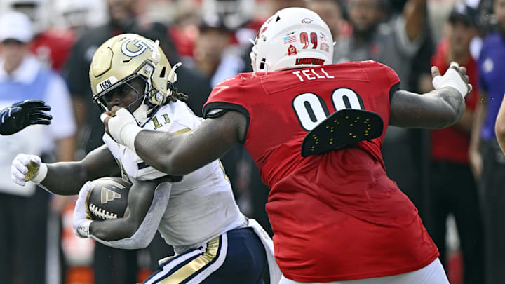 Sep 21, 2024; Louisville, Kentucky, USA; Georgia Tech Yellow Jackets running back Jamal Haynes (11) runs the ball despite the facemark from Louisville Cardinals defensive lineman Dezmond Tell (99) during the first quarter at L&N Federal Credit Union Stadium. Mandatory Credit: Jamie Rhodes-Imagn Images Sep 21, 2024; Louisville, Kentucky, USA; Georgia Tech Yellow Jackets running back Jamal Haynes (11) runs the ball despite the facemark from Louisville Cardinals defensive lineman Dezmond Tell (99) during the first quarter at L&N Federal Credit Union Stadium. Mandatory Credit: Jamie Rhodes-Imagn Images