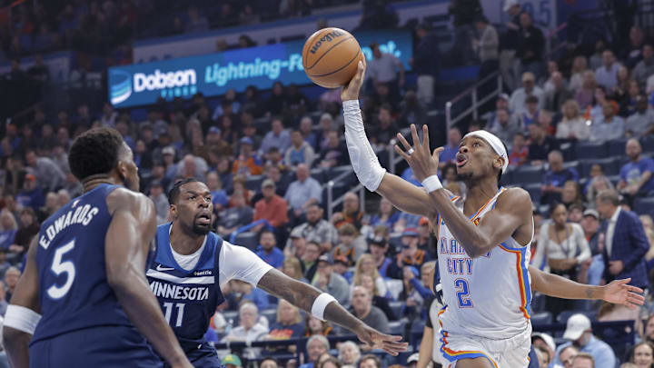 Feb 24, 2025; Oklahoma City, Oklahoma, USA; Oklahoma City Thunder guard Shai Gilgeous-Alexander (2) shoots as Minnesota Timberwolves center Naz Reid (11) and guard Anthony Edwards (5) defend during the first quarter at Paycom Center. Mandatory Credit: Alonzo Adams-Imagn Images