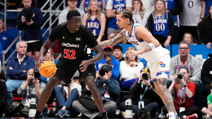 Feb 21, 2026; Lawrence, Kansas, USA; Cincinnati Bearcats center Moustapha Thiam (52) dribbles the ball as Kansas Jayhawks guard Jayden Dawson (1) defends during the second half of the game at Allen Fieldhouse. Mandatory Credit: Denny Medley-Imagn Images