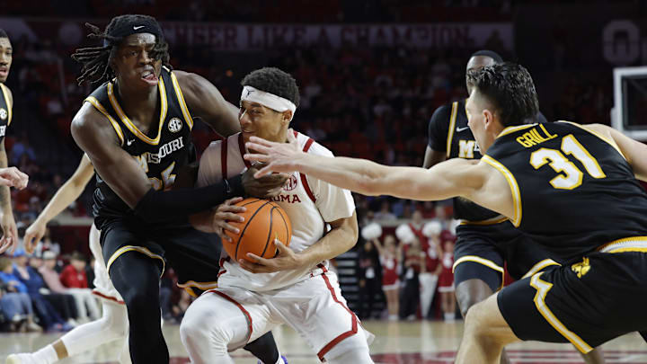 Mar 5, 2025; Norman, Oklahoma, USA; Oklahoma Sooners guard Jeremiah Fears (0) drives to the basket between Missouri Tigers guard Mark Mitchell (25) and guard Caleb Grill (31) during the second half at Lloyd Noble Center. Mandatory Credit: Alonzo Adams-Imagn Images Mar 5, 2025; Norman, Oklahoma, USA; Oklahoma Sooners guard Jeremiah Fears (0) drives to the basket between Missouri Tigers guard Mark Mitchell (25) and guard Caleb Grill (31) during the second half at Lloyd Noble Center. Mandatory Credit: Alonzo Adams-Imagn Images