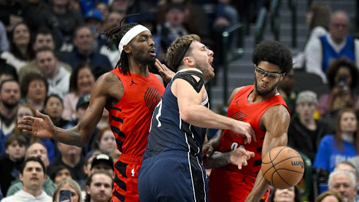 Jan 3, 2024; Dallas, Texas, USA; Dallas Mavericks guard Luka Doncic (77) is fouled as he drives to the basket between Portland Trail Blazers forward Jerami Grant (9) and guard Scoot Henderson (00) during the first quarter at the American Airlines Center. Mandatory Credit: Jerome Miron-Imagn Images Jan 3, 2024; Dallas, Texas, USA; Dallas Mavericks guard Luka Doncic (77) is fouled as he drives to the basket between Portland Trail Blazers forward Jerami Grant (9) and guard Scoot Henderson (00) during the first quarter at the American Airlines Center. Mandatory Credit: Jerome Miron-Imagn Images