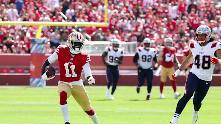 Sep 29, 2024; Santa Clara, California, USA; San Francisco 49ers wide receiver Brandon Aiyuk (11) runs with the ball past New England Patriots linebacker Jahlani Tavai (48) during the first quarter at Levi's Stadium. Mandatory Credit: Sergio Estrada-Imagn Images