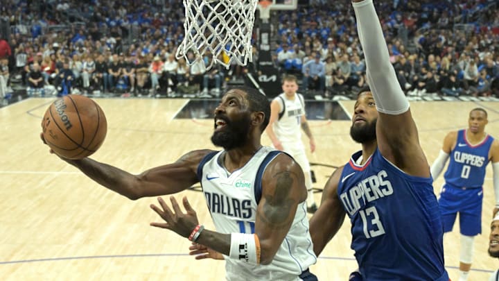  Apr 21, 2024; Los Angeles, California, USA; Dallas Mavericks guard Kyrie Irving (11) drives past Paul George for a bucket. 