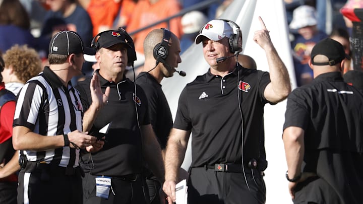 Oct 12, 2024; Charlottesville, Virginia, USA; Louisville Cardinals head coach Jeff Brohm (center) questions a call against the Virginia Cavaliers during the first half at Scott Stadium. Mandatory Credit: Amber Searls-Imagn Images