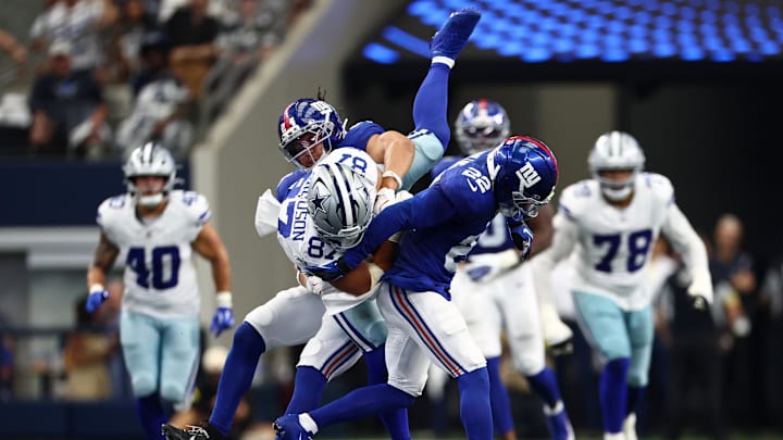 Sep 14, 2025; Arlington, Texas, USA; Dallas Cowboys tight end Jake Ferguson (87) gets tripped up with New York Giants cornerback Dru Phillips (22) during the third quarter at AT&T Stadium. 