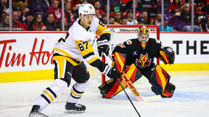 Oct 22, 2024; Calgary, Alberta, CAN; Pittsburgh Penguins right wing Rickard Rakell (67) controls the puck in front of Calgary Flames goaltender Dustin Wolf (32) during the third period at Scotiabank Saddledome. Mandatory Credit: Sergei Belski-Imagn Images