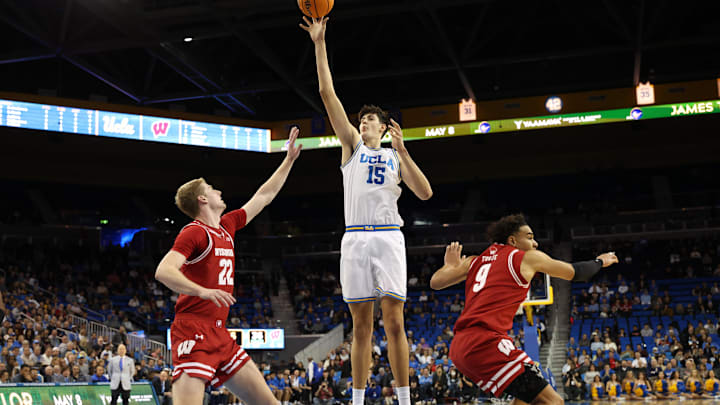 Jan 21, 2025; Los Angeles, California, USA;  UCLA Bruins center Aday Mara (15) shoots the ball between Wisconsin Badgers forward Steven Crowl (22) and Wisconsin Badgers guard John Tonje (9) during the first half at Pauley Pavilion presented by Wescom. Mandatory Credit: Kiyoshi Mio-Imagn Images