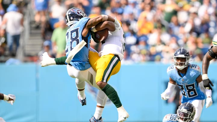 Sep 22, 2024; Nashville, Tennessee, USA;  Tennessee Titans safety Quandre Diggs (28) hits Green Bay Packers running back Emanuel Wilson (31) in the air during the second half at Nissan Stadium.