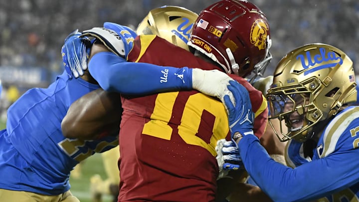 Nov 23, 2024; Pasadena, California, USA; UCLA Bruins defensive back Ramon Henderson (11), linebacker Carson Schwesinger (in back), and linebacker Kain Medrano (20) try to stop USC Trojans wide receiver Kyron Hudson (10) during the fourth quarter at Rose Bowl. Mandatory Credit: Robert Hanashiro-Imagn Images Nov 23, 2024; Pasadena, California, USA; UCLA Bruins defensive back Ramon Henderson (11), linebacker Carson Schwesinger (in back), and linebacker Kain Medrano (20) try to stop USC Trojans wide receiver Kyron Hudson (10) during the fourth quarter at Rose Bowl. Mandatory Credit: Robert Hanashiro-Imagn Images