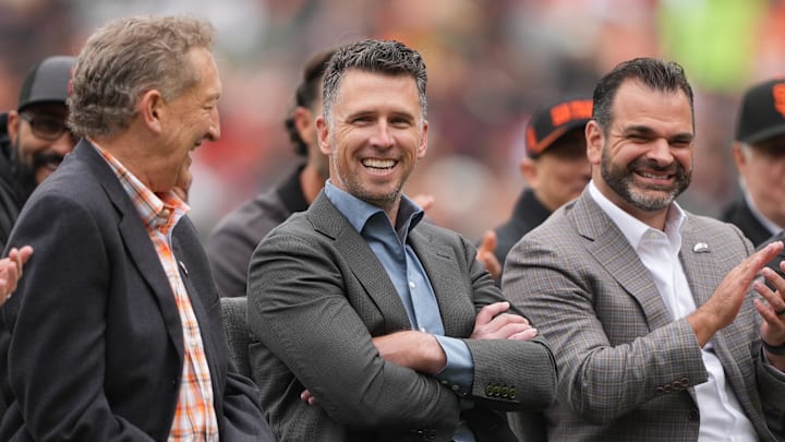 Apr 25, 2026; San Francisco, California, USA; San Francisco Giants president of baseball operations Buster Posey (center) sits on the field with president Larry Baer (left) and general manager Zack Minasian (right) before the game against the Miami Marlins at Oracle Park. Mandatory Credit: Darren Yamashita-Imagn Images