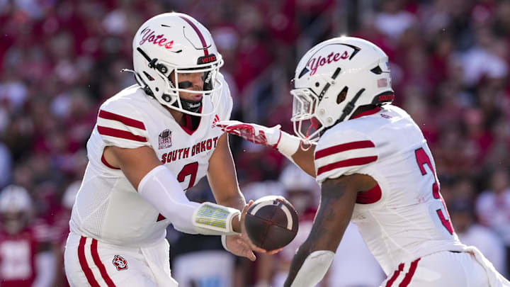 South Dakota quarterback Aidan Bouman hands the football to running back Charles Pierre Jr.