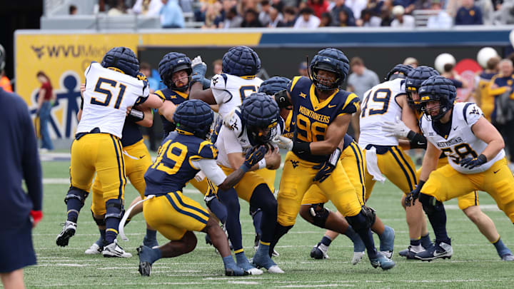 West Virginia University safety William Davis (49) and defensive lineman Brandon Caesar (98) converge on quarterback Scott Dean (12).