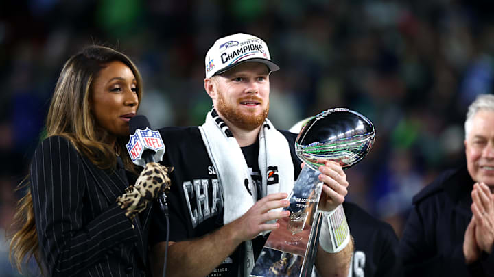 Feb 8, 2026; Santa Clara, CA, USA; Seattle Seahawks quarterback Sam Darnold (14) celebrates with the Vince Lombardi trophy on the podium after defeating the New England Patriots in Super Bowl LX at Levi's Stadium. Mandatory Credit: Mark J. Rebilas-Imagn Images