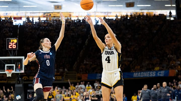 Iowa guard Kylie Feuerbach (4) attempts a 3-pointer as FDU’s Madlena Gerke (0) defends March 21, 2026 during a First Round NCAA March Madness game at Carver-Hawkeye Arena in Iowa City, Iowa.