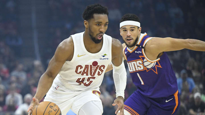 Jan 20, 2025; Cleveland, Ohio, USA; Cleveland Cavaliers guard Donovan Mitchell (45) dribbles beside Phoenix Suns guard Devin Booker (1) in the first quarter at Rocket Mortgage FieldHouse. Mandatory Credit: David Richard-Imagn Images
