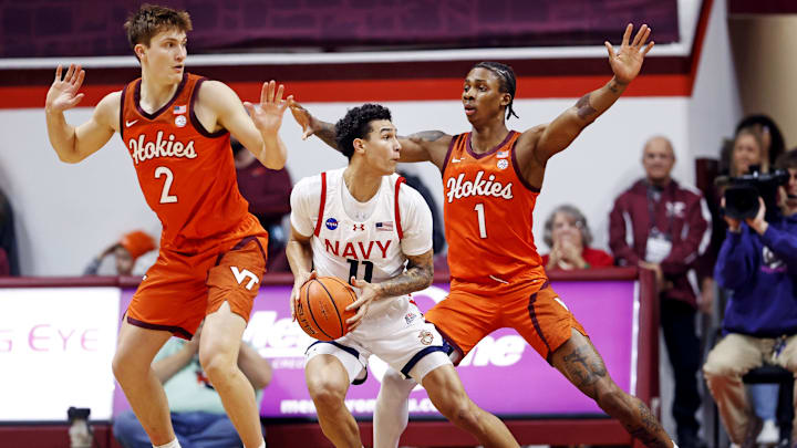 Dec 15, 2024; Blacksburg, Virginia, USA; Navy Midshipmen forward Donovan Draper (11) drives to the basket against Virginia Tech Hokies forward Tobi Lawal (1) and guard Jaden Schutt (2) during the first half at Cassell Coliseum. Mandatory Credit: Peter Casey-Imagn Images