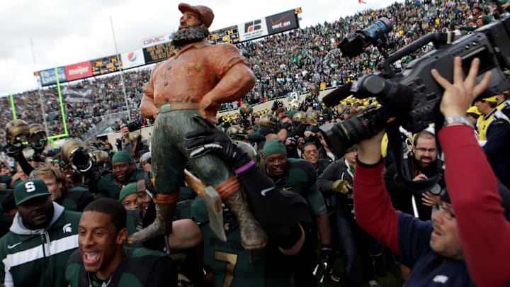 Michigan State players hold up the Paul Bunyan Trophy and run it around the field after their 28-14 win against Michigan at Spartan Stadium on Oct. 15, 2011.