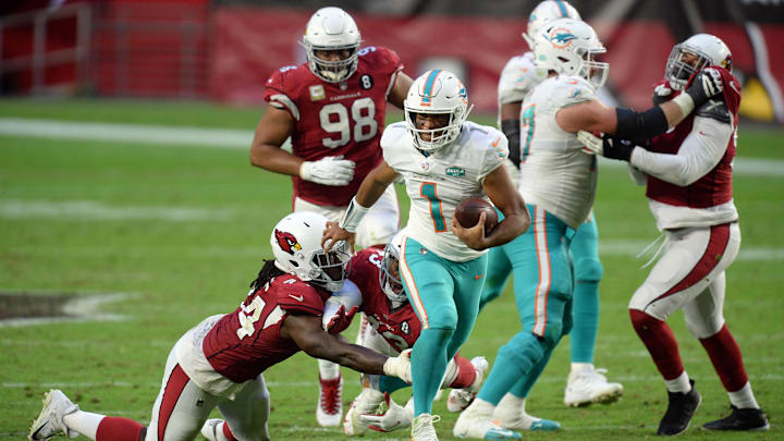 Miami Dolphins quarterback Tua Tagovailoa (1) breaks the tackle of Arizona Cardinals linebacker Markus Golden (44) and Arizona Cardinals cornerback Byron Murphy (33) during the second half at State Farm Stadium in 2020.