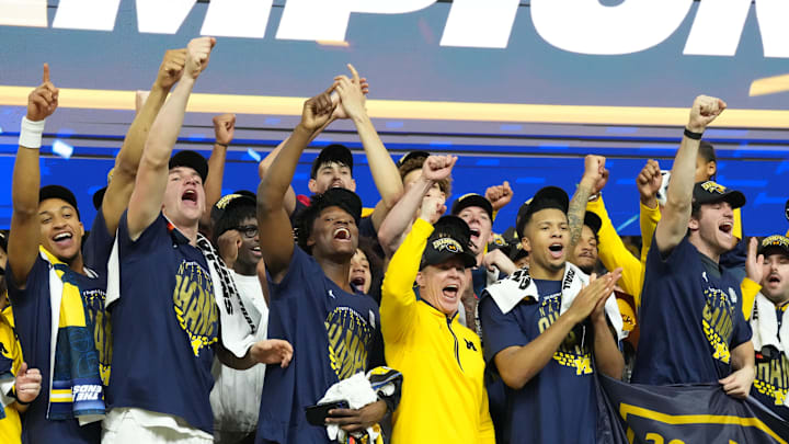 Apr 6, 2026; Indianapolis, IN, USA; Michigan Wolverines head coach Dusty May celebrates with his players on stage after defeating the Connecticut Huskies in the national championship of the Final Four of the men's 2026 NCAA Tournament at Lucas Oil Stadium. Mandatory Credit: Robert Deutsch-Imagn Images Apr 6, 2026; Indianapolis, IN, USA; Michigan Wolverines head coach Dusty May celebrates with his players on stage after defeating the Connecticut Huskies in the national championship of the Final Four of the men's 2026 NCAA Tournament at Lucas Oil Stadium. Mandatory Credit: Robert Deutsch-Imagn Images
