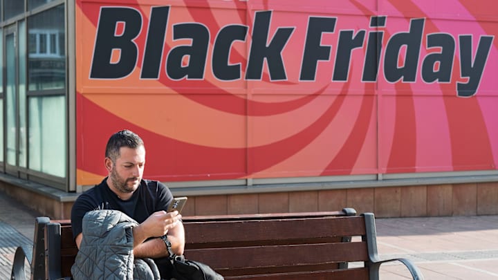 A man uses his smartphone while sitting on a bench, with a...