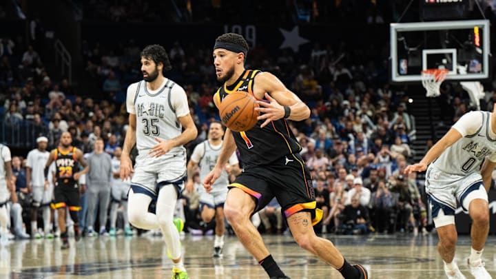 Dec 8, 2024; Orlando, Florida, USA; Phoenix Suns guard Devin Booker (1) dribbles the ball past Orlando Magic guard Anthony Black (0) in the fourth quarter at Kia Center. Mandatory Credit: Jeremy Reper-Imagn Images