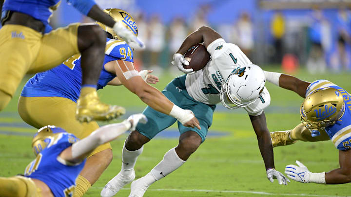 Sep 2, 2023; Pasadena, California, USA;  Coastal Carolina Chanticleers running back Braydon Bennett (1) is stopped by UCLA Bruins defensive lineman Dovid Magna (94) and linebacker Darius Muasau (53) in the first half at Rose Bowl. Mandatory Credit: Jayne Kamin-Oncea-Imagn Images