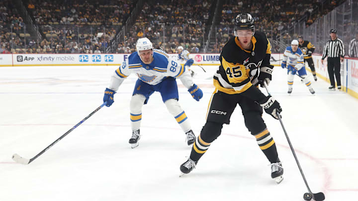 Oct 27, 2025; Pittsburgh, Pennsylvania, USA;  Pittsburgh Penguins defenseman Harrison Brunicke (45) handles the puck ahead of St. Louis Blues left wing Pavel Buchnevich (89) during the first period  at PPG Paints Arena. Mandatory Credit: Charles LeClaire-Imagn Images