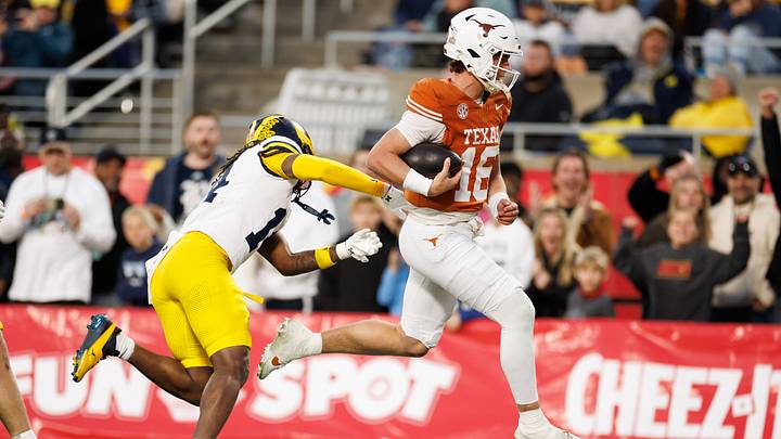 Texas Longhorns quarterback Arch Manning (16) runs with the ball past Michigan Wolverines defensive back Jordan Young (14) for a touchdown during the second half at Camping World Stadium. 