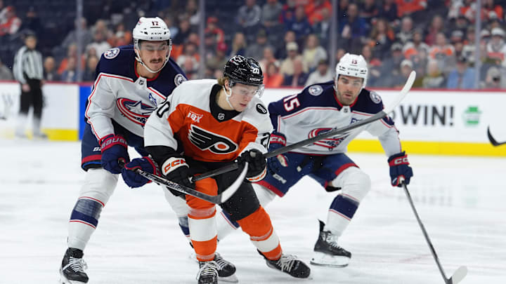 Mar 24, 2026; Philadelphia, Pennsylvania, USA; Philadelphia Flyers left wing Alex Bump (20) battles for the puck against Columbus Blue Jackets left wing Mason Marchment (17) and defenseman Dante Fabbro (15) in the first period at Xfinity Mobile Arena. Mandatory Credit: Kyle Ross-Imagn Images
