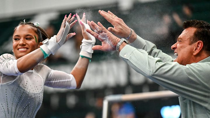 Michigan State's coach Mike Rowe, right, celebrates with Skyla Schulte after her in the bars routine