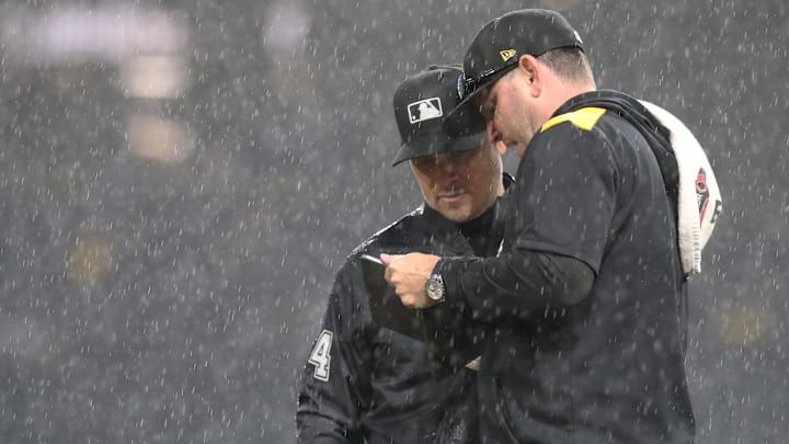 May 22, 2025; Pittsburgh, Pennsylvania, USA;  Pittsburgh Pirates grounds crew chief Mattt Brown (right) talks with MLB umpire crew chief Mark Wegner (14) as a heavy rain delays the game against the Milwaukee Brewers in the sixth inning at PNC Park. Mandatory Credit: Charles LeClaire-Imagn Images