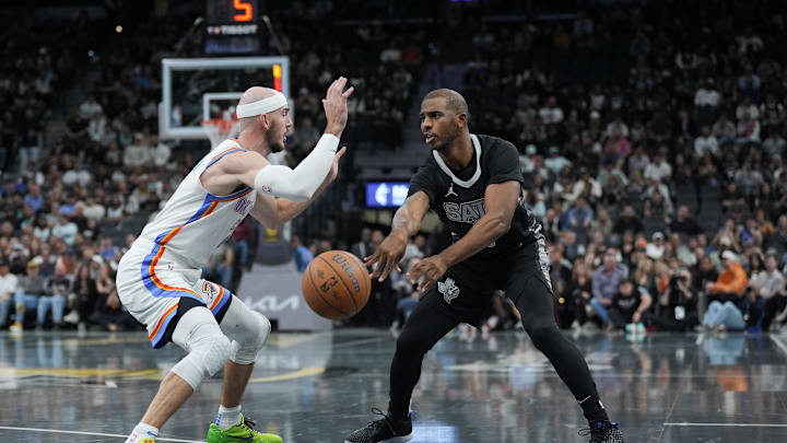 Nov 19, 2024; San Antonio, Texas, USA;  San Antonio Spurs guard Chris Paul (3) passes the ball in front of Oklahoma City Thunder guard Alex Caruso (9) in the first half at Frost Bank Center. Mandatory Credit: Daniel Dunn-Imagn Images