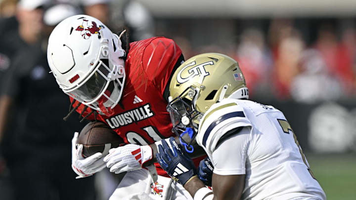 Sep 21, 2024; Louisville, Kentucky, USA;  Louisville Cardinals running back Donald Chaney (21) tries to break free from the tackle of Georgia Tech Yellow Jackets defensive back Taye Seymore (7) during the first half at L&N Federal Credit Union Stadium. Mandatory Credit: Jamie Rhodes-Imagn Images