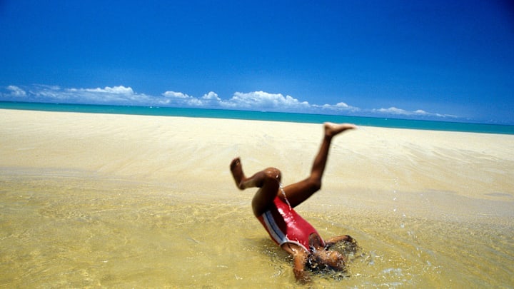 Afro-Brazilian 10-years old girl plays in a pond formed by...