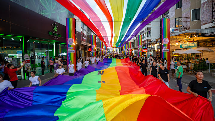 Members of the LGBTQIA+ community hold a rainbow flag during...