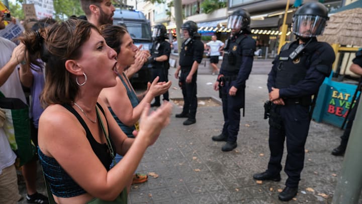 Protesters are seen shouting slogans in front of a line of...